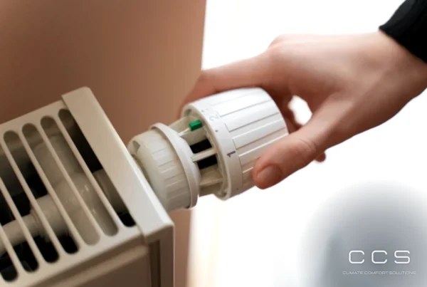 Dłoń ustawiająca głowicę termostatyczną grzejnika – wpływ zasłon i zabudowy na pomiar